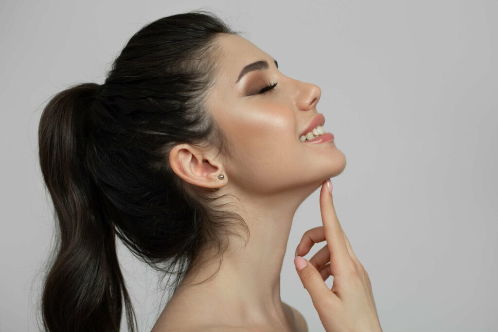 A smiling patient showcasing a defined jawline after undergoing double chin removal in Delhi.